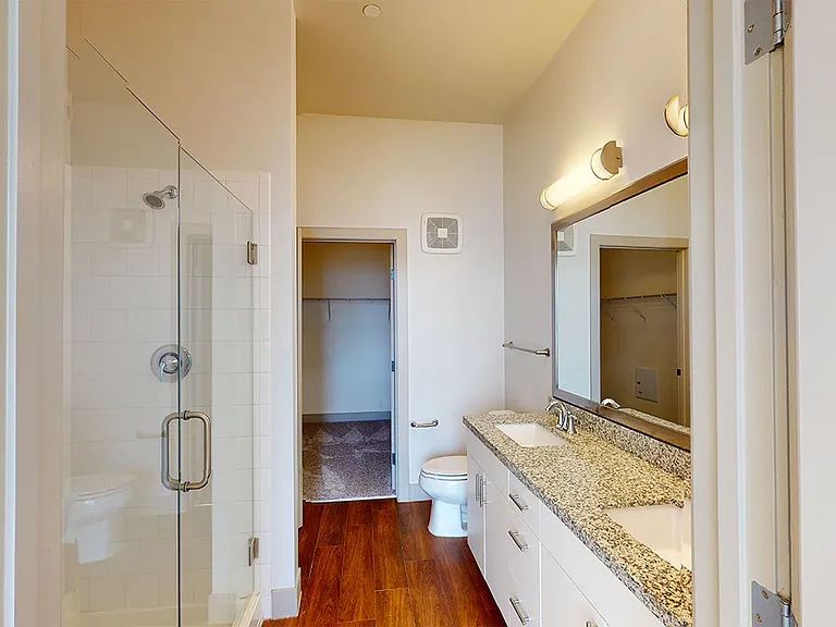 Apartment bathroom with wood-style flooring and double sinks.