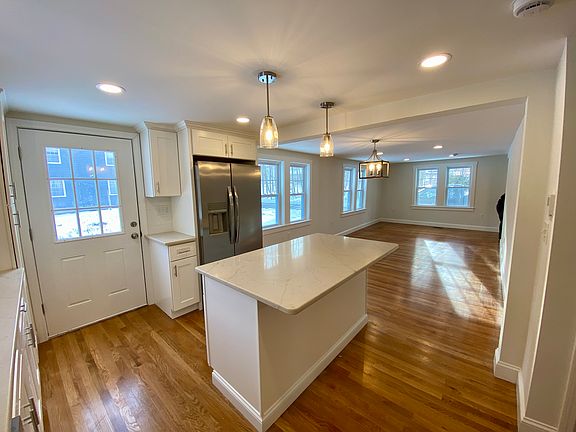 New kitchen with island and pendant lighting. Kitchen door gives access to driveway/backyard.