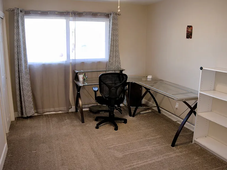 Bedroom 3 is set up with L shaped desk, chair, bookcase, ironing board and iron, hi-speed wifi extender, whiteboard