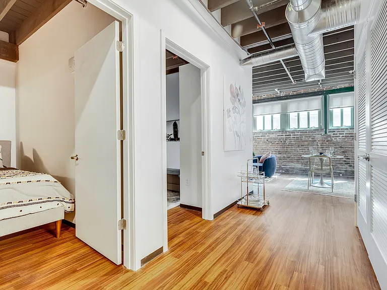 Transitioning Spaces: An inviting hallway with glimpses into adjacent rooms, unified by warm wooden flooring and rustic overhead beams.