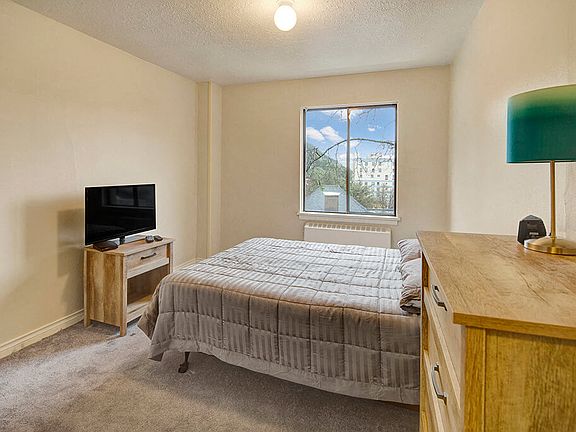 A bedroom with overhead lighting and a window overlooking the property