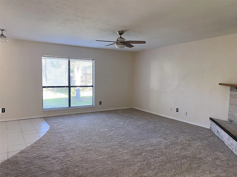 Unfurnished living room featuring ceiling fan and carpet floors