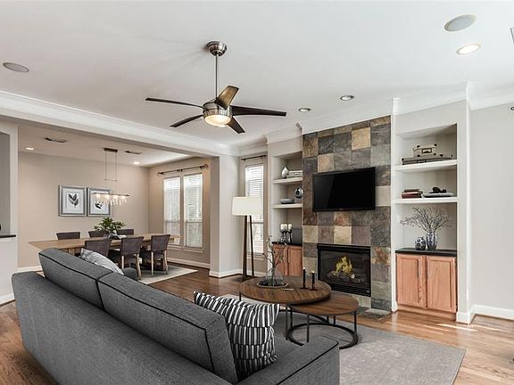 Second floor has open Living Room, Dining Room in background, and Kitchen seen through opening on left. Look at the number of windows and those gleaming recently finished hardwood floors! Photo virtually staged.