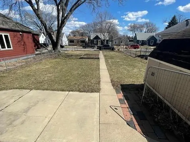 Large fenced in front yard with garden and shed.