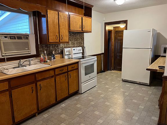 Kitchen, replaced flooring, double sink, glass-top electric range, refrigerator, and extended countertop to allow eating, work space, etc. Opens to laundry room.