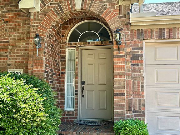 Doorway to property with brick siding and an attached garage