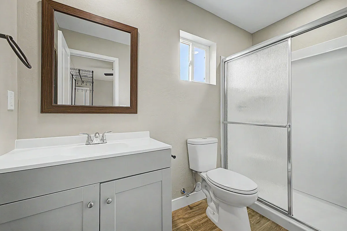 Bathroom with a wide vanity, framed mirror, window for ventilation, and a sliding glass shower enclosure. - E Princess Dr
