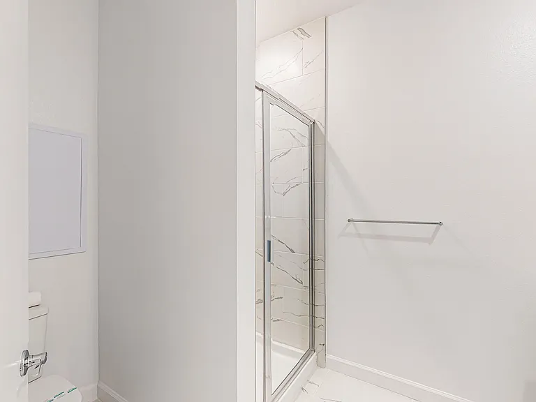 Clean bathroom with a glass-enclosed shower and large-format tile surround, plus a convenient towel bar for daily use.