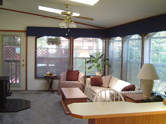 Family room with wood stove, ceiling fan, and door to the deck