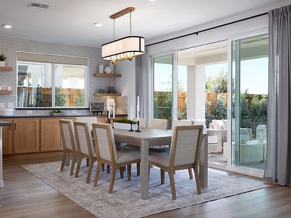A modern and spacious dining room with a wooden table, upholstered chairs, and a large window overlo
