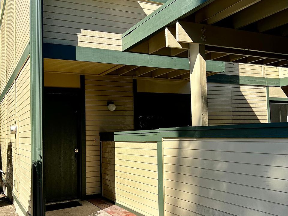 Front door. Photo shows one of two second story balconies, one of two enclosed patios below, and part of the carport. Condo is detached on one side.