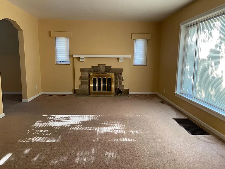 Large living room with fireplace and picture window with lots of natural light.