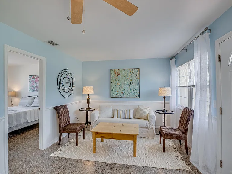 Large furnished living room with terrazzo floor, adjacent to two bedrooms