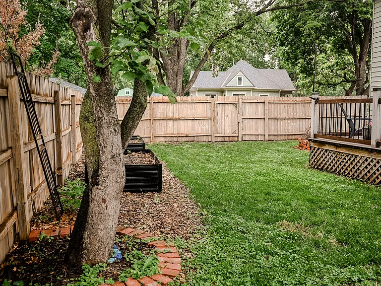 Fully fenced in backyard with raised garden bed and chicken coup with 2 storage sheds.
