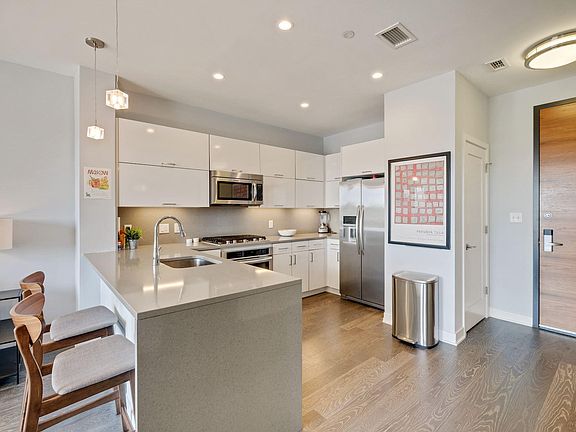 Quartz counters with waterfall edge, peninsula with overhang for bar stools and high gloss cabinets.