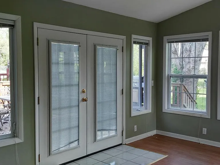 Green, relaxing living room with double doors for easy access to the patio.