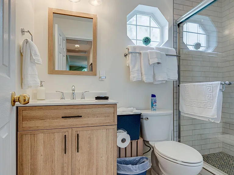 Secondary bath with step-in shower of beautiful tiling. Quaint window and vanity