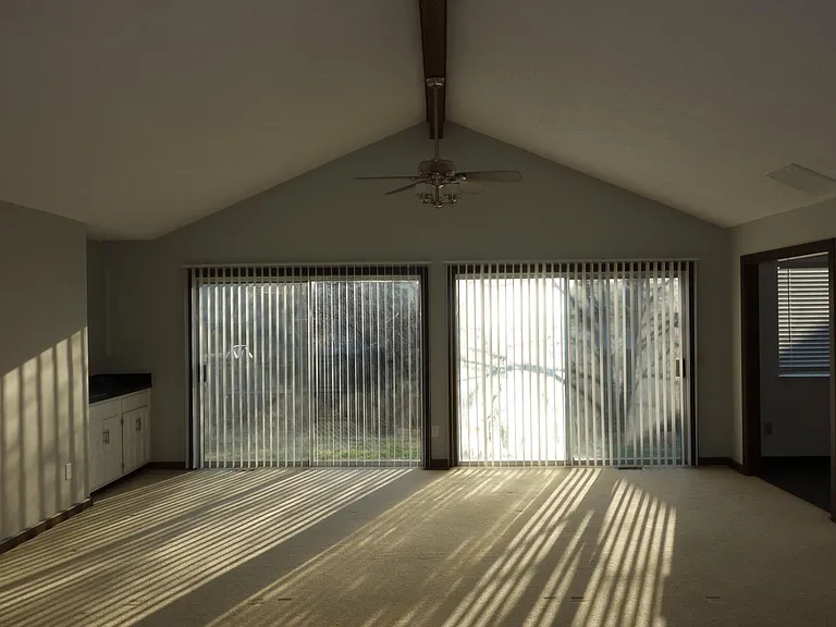another view of living room. was not the best time of day to take this picture. Bar on left and kitchen access on right. *These sliding glass doors are being replaced!*