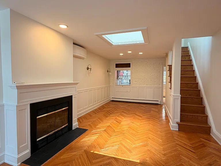 Open concept living and dining area on the first floor. Includes unique herringbone floors, decorative fireplace, and two story skylight.