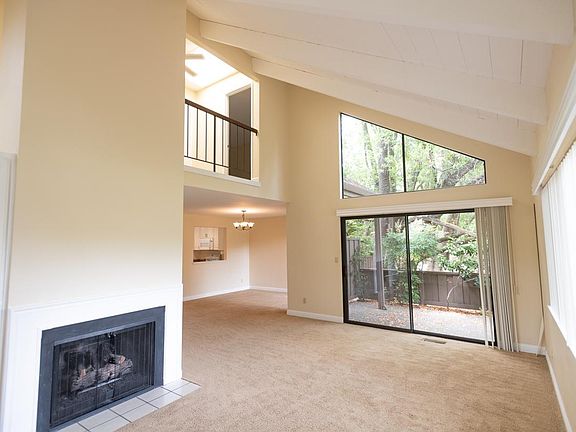 view of vaulted living room, private patio, glimpse of dining area