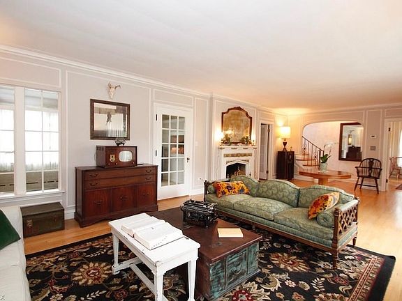 Large living room with wood burner fireplace.  There is plenty of space for large scale furnishings. Facing sunroom at the rear of the house and main staircase.