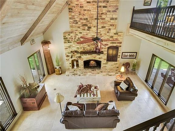 Family room has floor to ceiling brick fireplace, tile floors, whitewashed ceilings and walls of win
