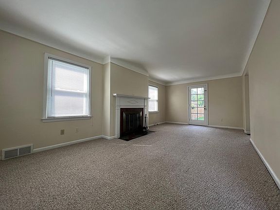 Spacious living room with lot of natural light, natural fireplace, and French door to back porch