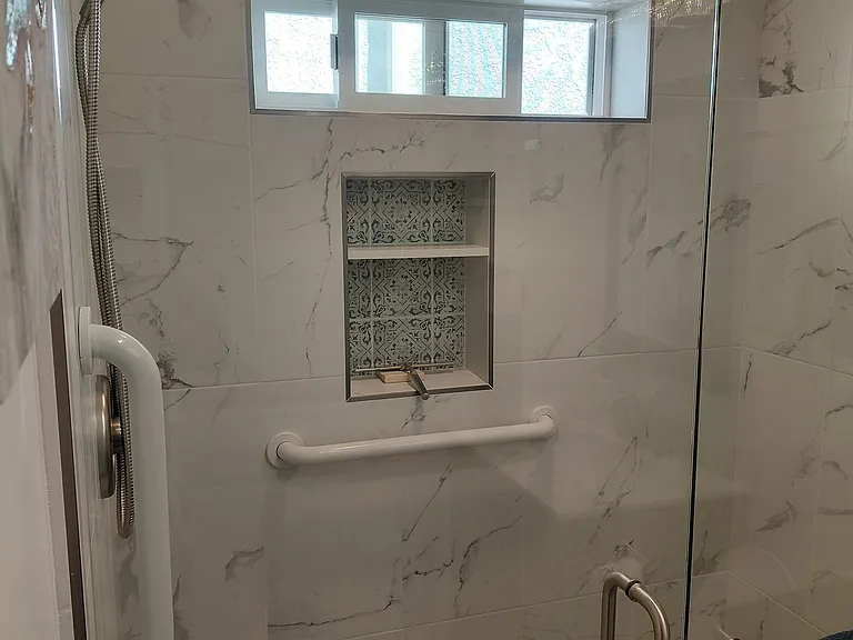Walk-in Shower with glass shower door, grab bars, custom tile and storage shelves