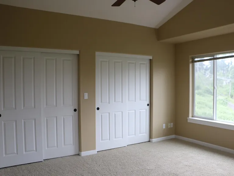 Master Bedroom showing the closet doors and large picture window. Master Bedroom has a ceiling fan.