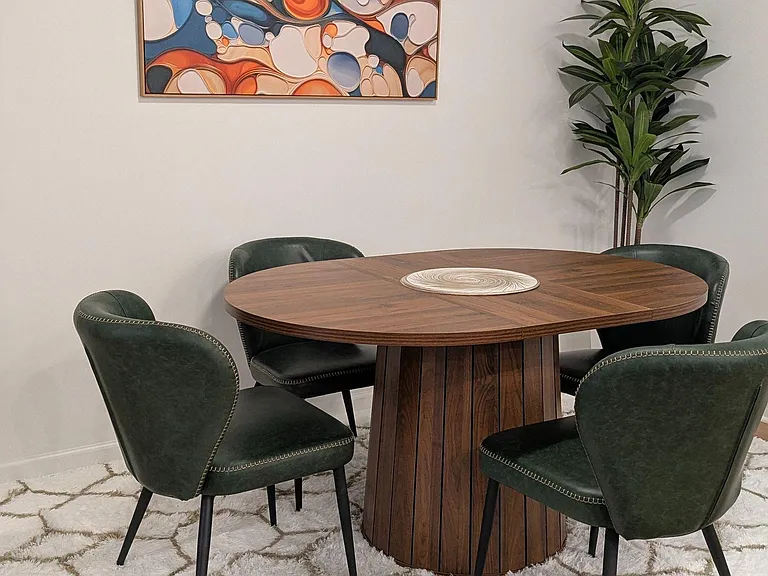 Dedicated dining area with a round table for four, cushioned chairs, and wall artideal for meals or shared work time.