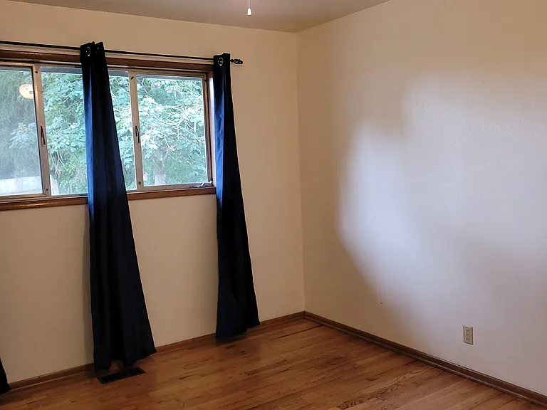Bedroom #2 in the front of house has real hardwood floors, a large window, a ceiling fan and the window faces the back yard.