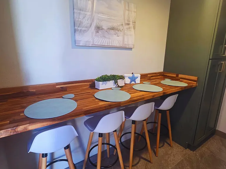 Enjoy meals at a stylish bar table with 4 seats and beautiful artwork.