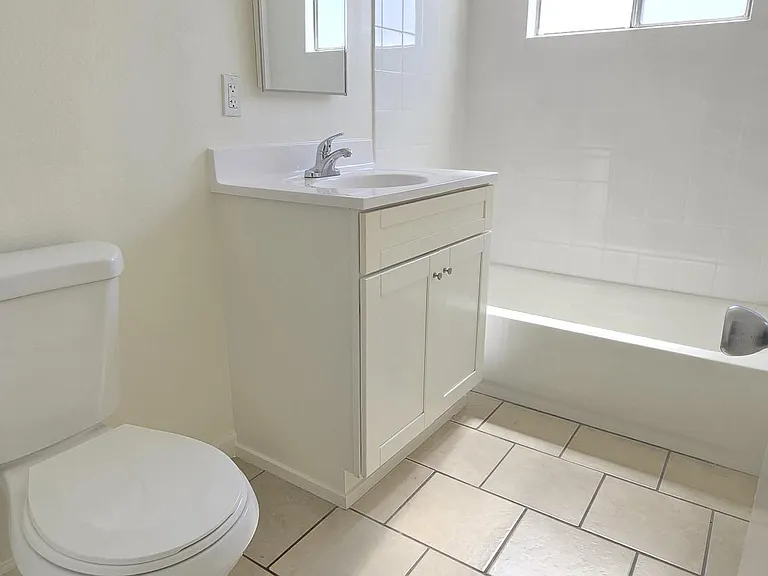 Bathroom with new vanity and tiled tub surround.