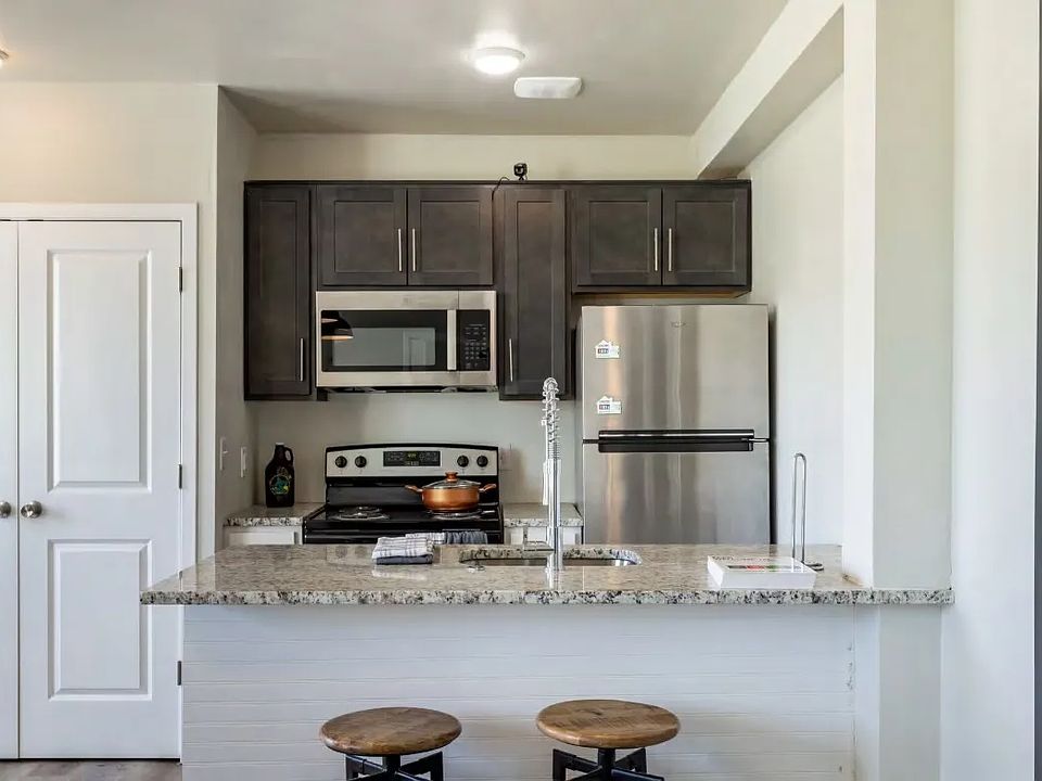 Sleek kitchen with stainless steel appliances, quartz countertops, and breakfast bar seating.