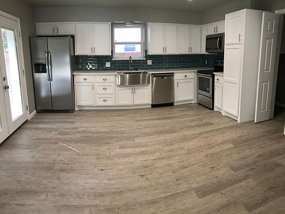 Fully open kitchen with new shaker style cabinets, farm sink, quartz countertops, new stainless steel appliances with an eye-catching glass subway tile backsplash!