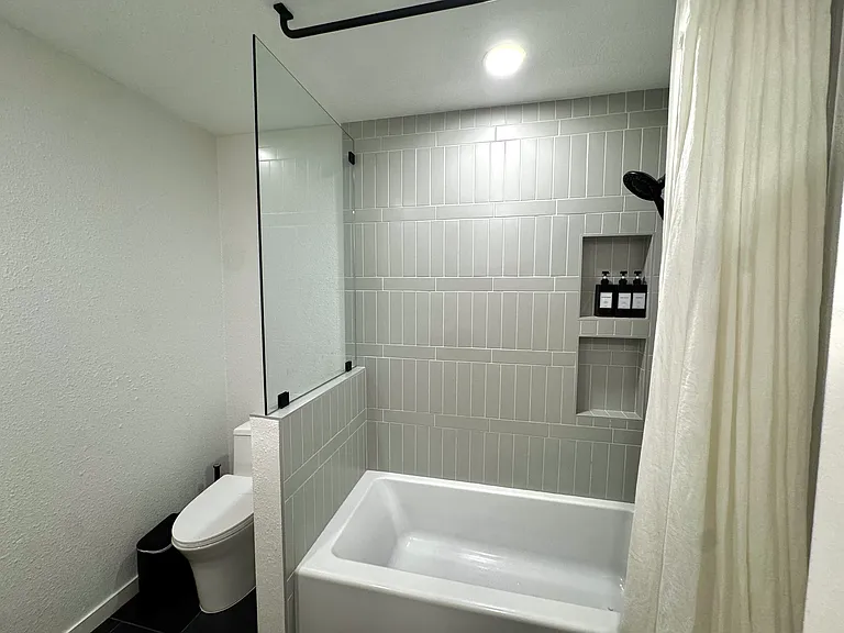 A spacious tub/shower combination. Thoughtfully updated with contemporary finishes and abundant storage.