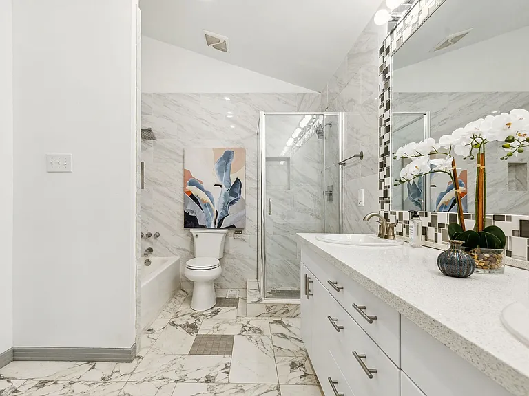 Bathroom featuring a dual vanity with a quartz countertop, a walk-in shower with a glass enclosure, a built-in bathtub, and marble-look tile flooring