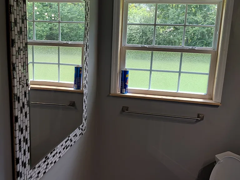 Master bathroom has large window and custom mirror with matching backsplash with the sinks and shower.