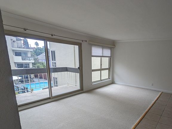 Living room and sliding glass doors out to private deck with a view of the pool.