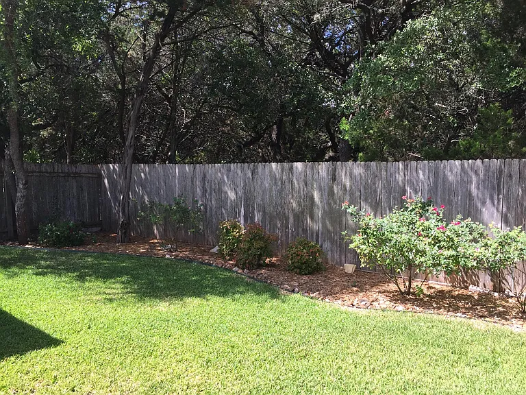 Landscaped backyard faces wooded acreage for park-like setting