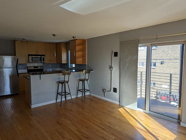 The kitchen/living area (paint and lighting have been updated and an automatic window covering has been added to the sliding glass door that leads to the balcony)