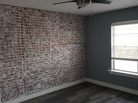 The master bedroom with beautifully crafted wood floors and a touch of urban charm that strikes a brick wall serving as a focal point.