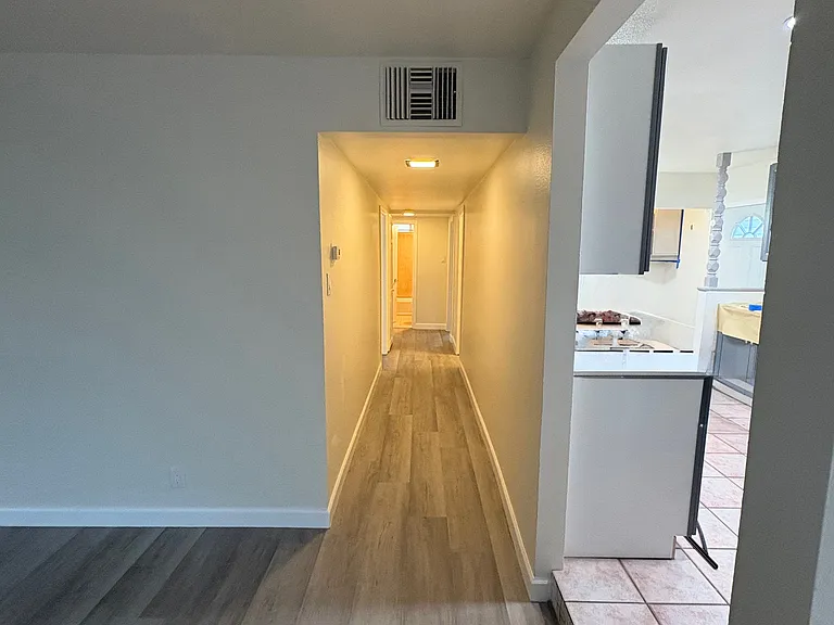 Exiting kitchen into living room, dining room to the right (not visible), entry to kitchen on the right, looking toward central hallway