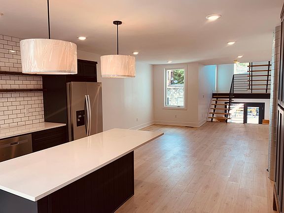 From the front door, see across the kitchen island, the living room area and the custom designed stairs which lead to the yard and also upstairs to the bedrooms