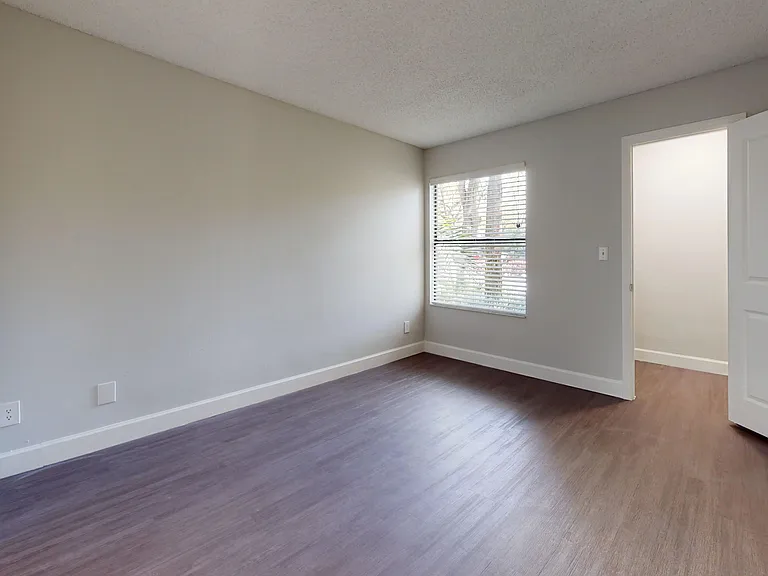 Experience comfort in the spacious bedroom featuring large windows for natural light and stylish wood-style flooring.