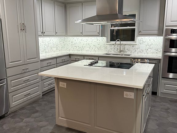 Renovated kitchen features beautiful white quarters counters with gray veins throughout.