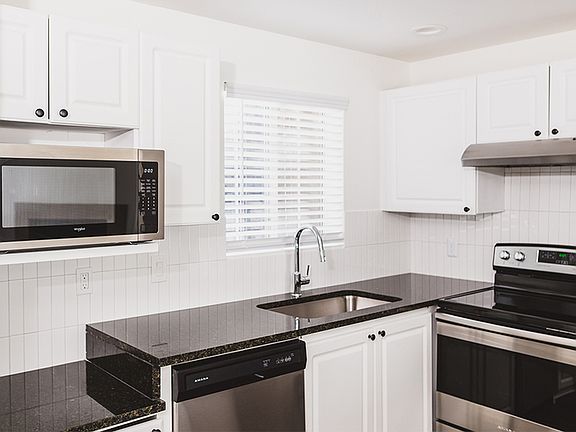Gourmet kitchens with granite countertops, custom white cabinetry with chrome pulls