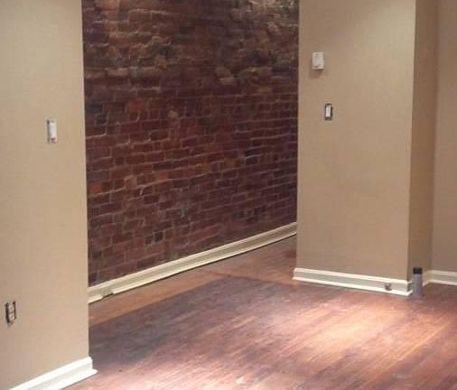Living room w/hardwood floors / hallway with exposed brick wall