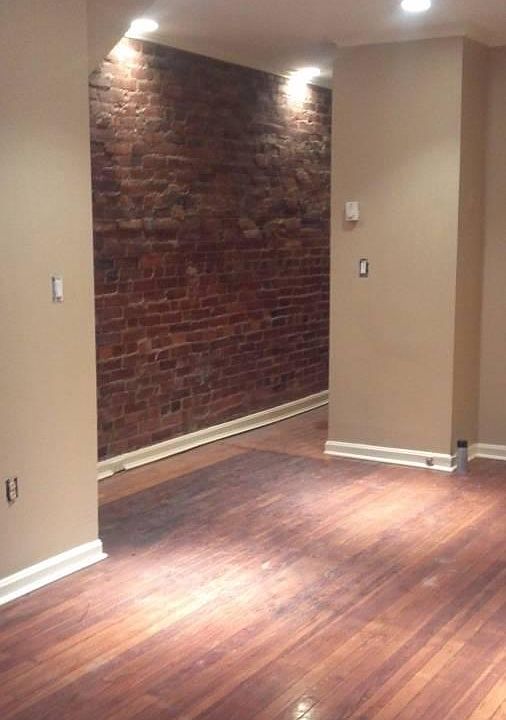 Living room w/hardwood floors / hallway with exposed brick wall