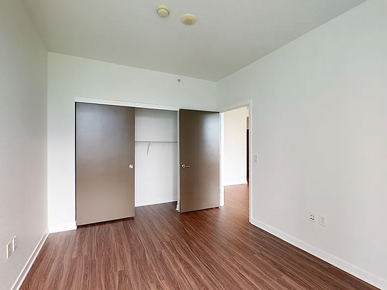 Spacious apartment bedroom with wood-style flooring.